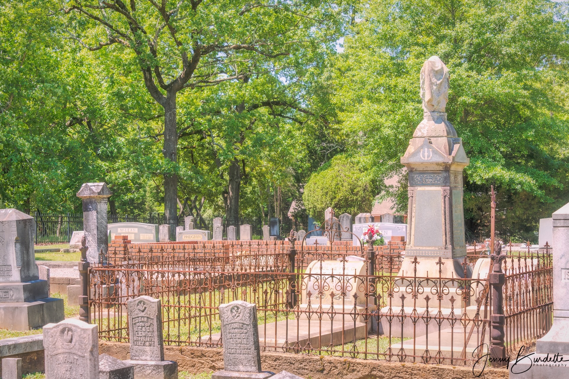 I. G. Woolsey monument and iron fence surrounded by historic headstones and oak trees