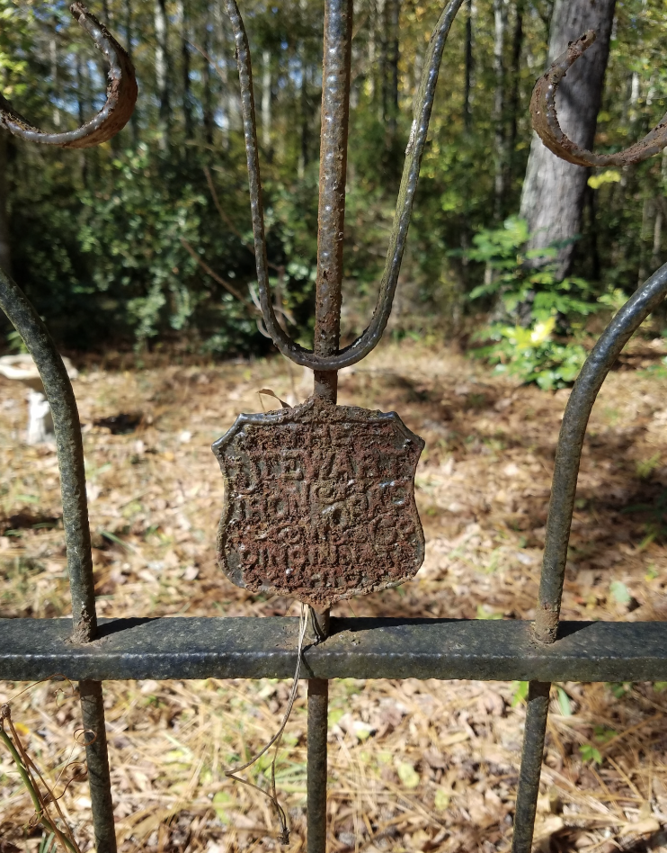 Close up of the historic Stewart Iron Company fence plaque showing heavy rust and weathered details.