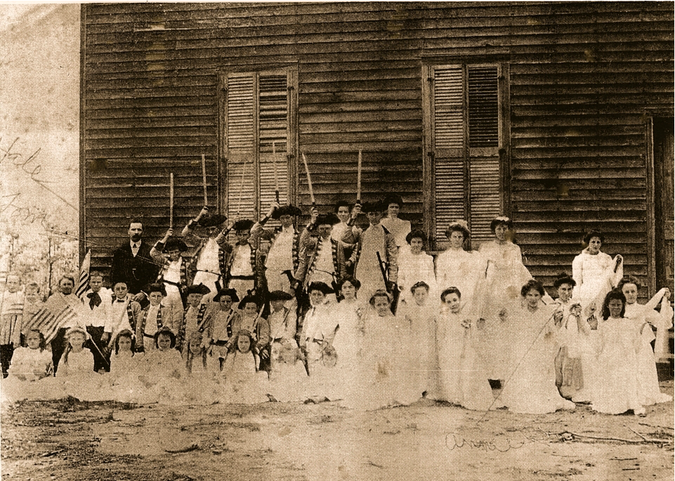 Vintage photograph of the early Woolsey schoolhouse with students and staff.